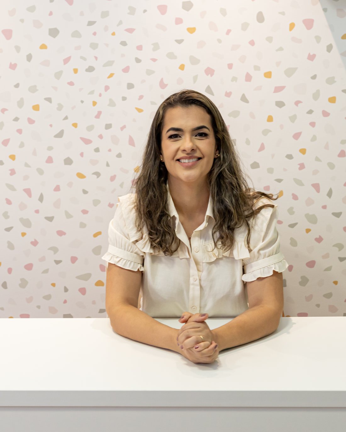 Letícia Dutra, terapeuta ocupacional, sentada à mesa da recepção do consultório